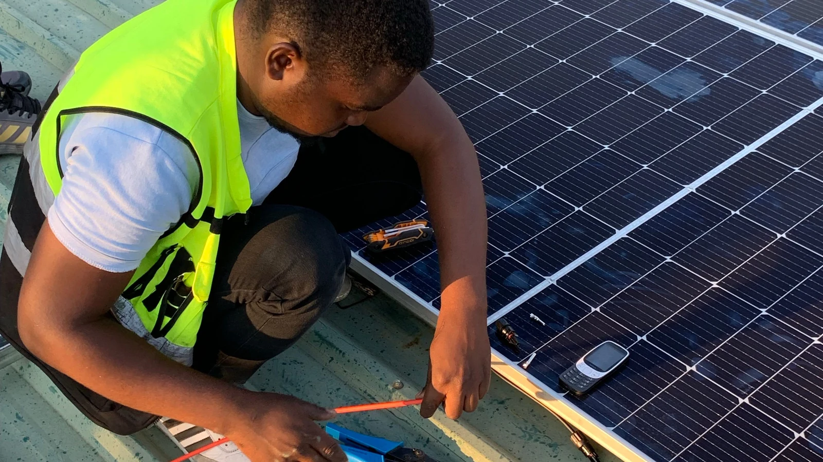 Technicien vérifiant câbles et panneaux photovoltaïques sur une toiture