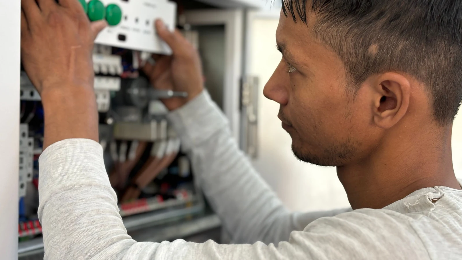 Technicien contrôlant les raccordements et protections d’un tableau électrique